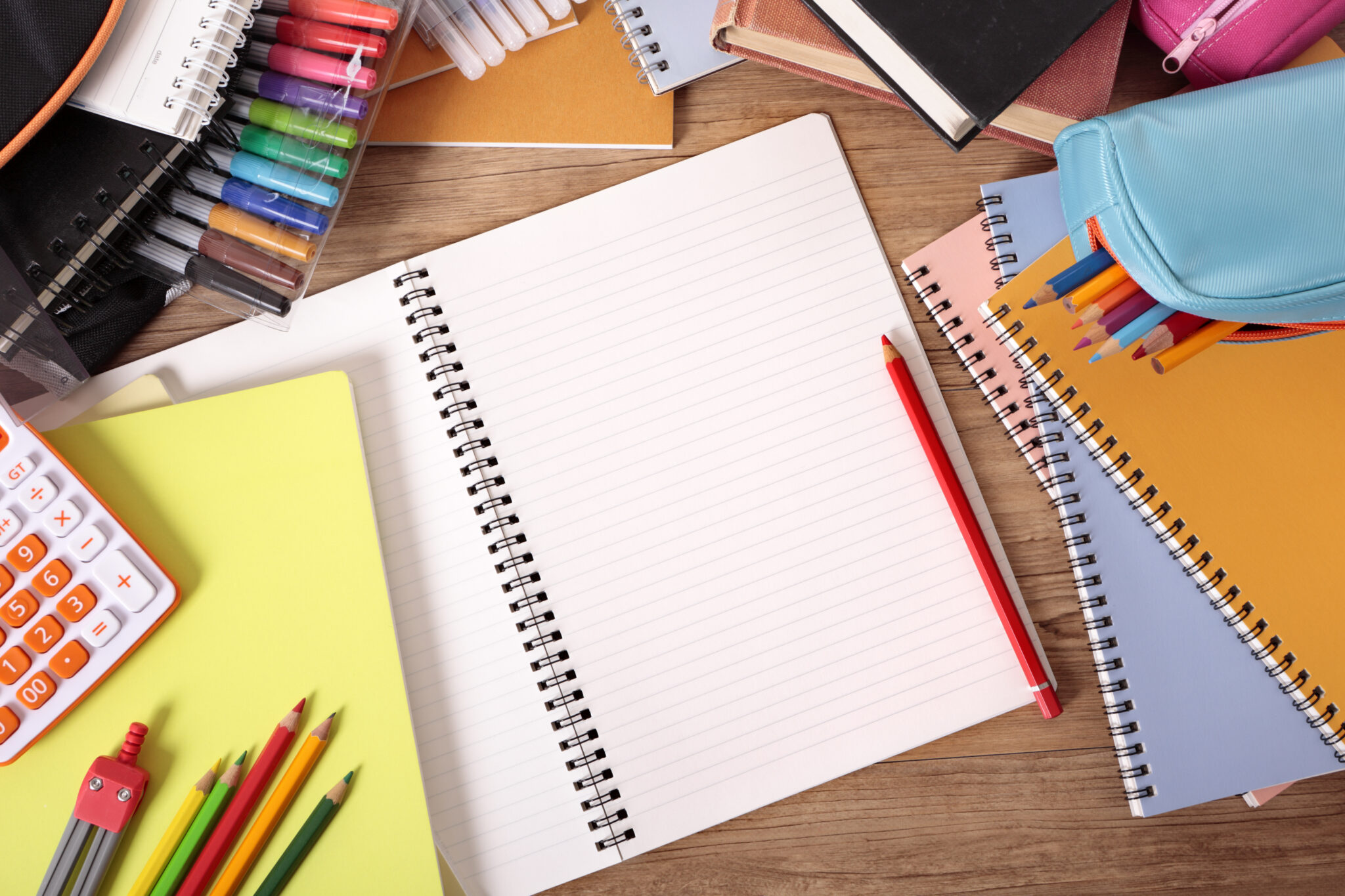 Busy student&rsquo;s desk with blank open notebook